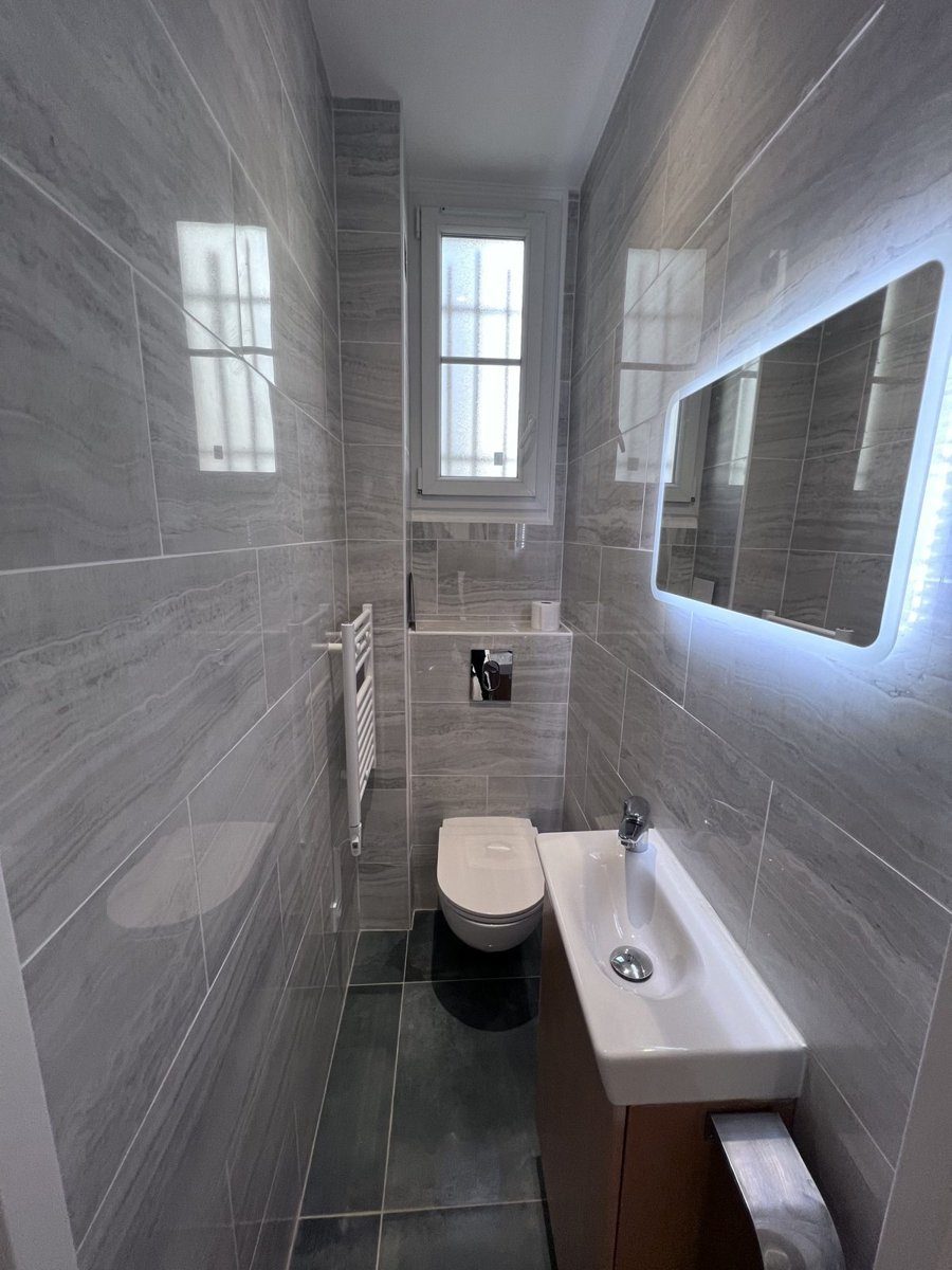 WC rénové avec faïence grise grand format, cuvette suspendue et lave-mains